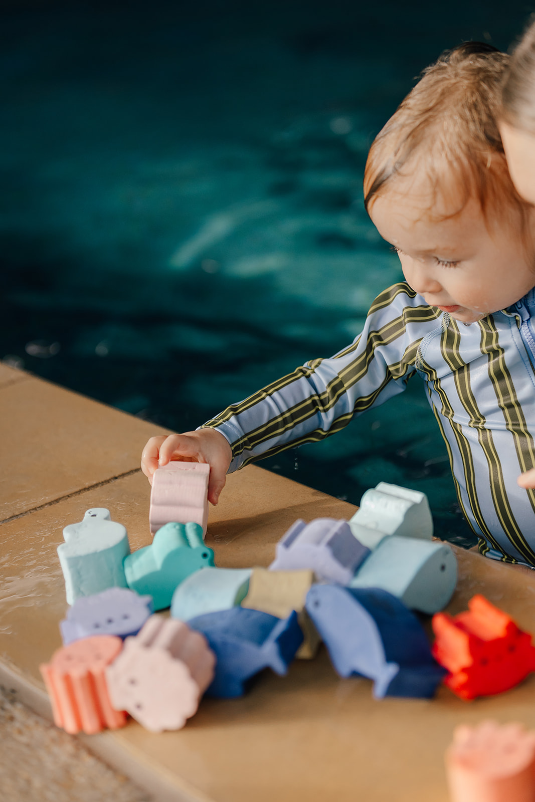 Baby playing with pool toys at Tri Swimming