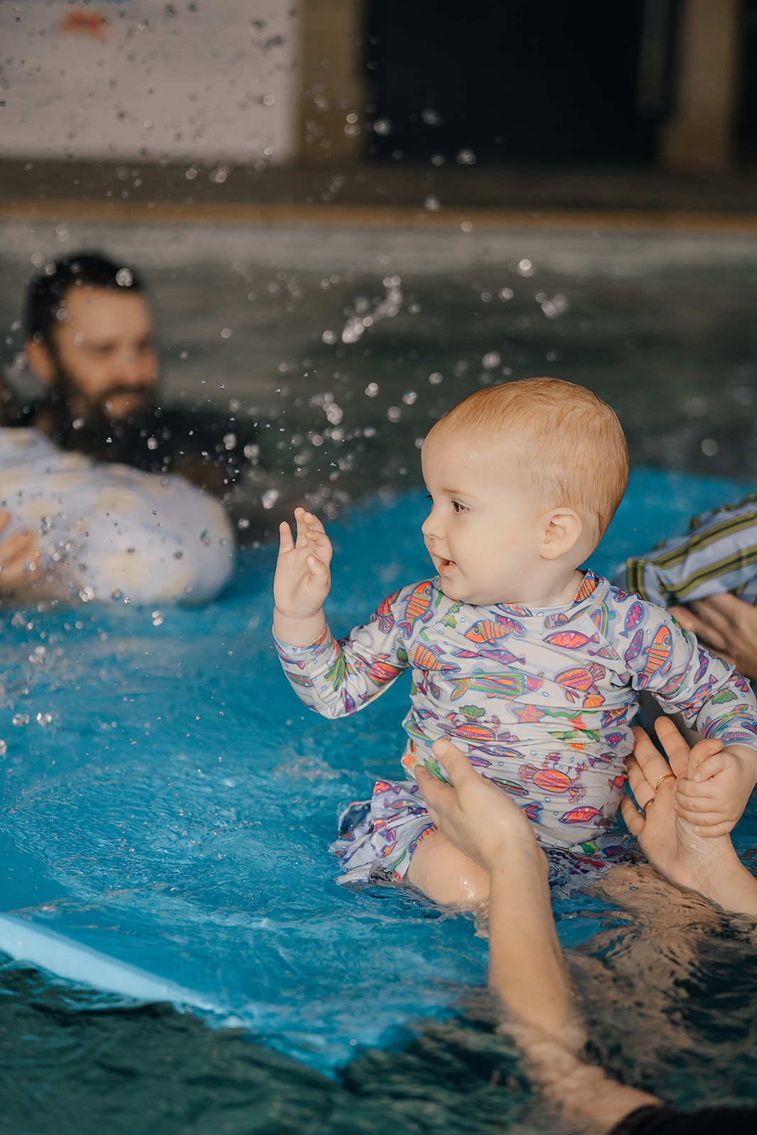 Baby reaching for pool toys at Tri Swimming