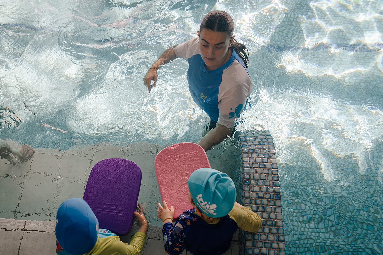 children with kick boards in the pool