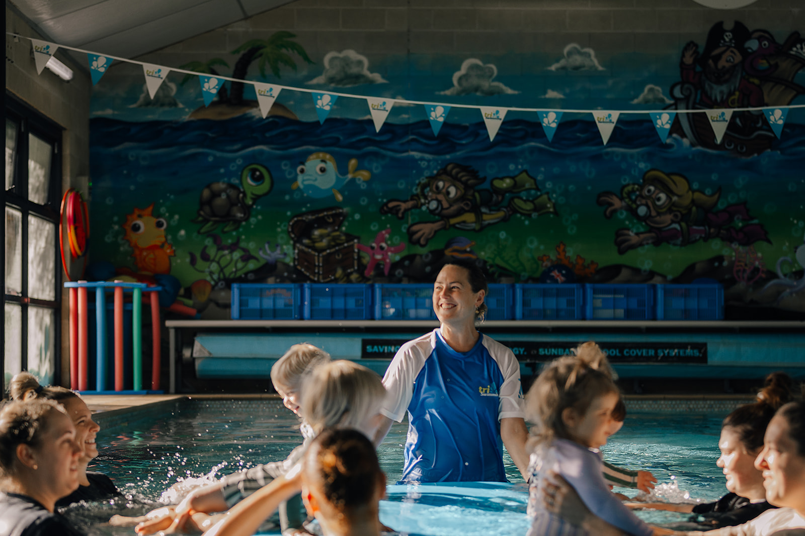 Smiling teacher with baby class in the pool