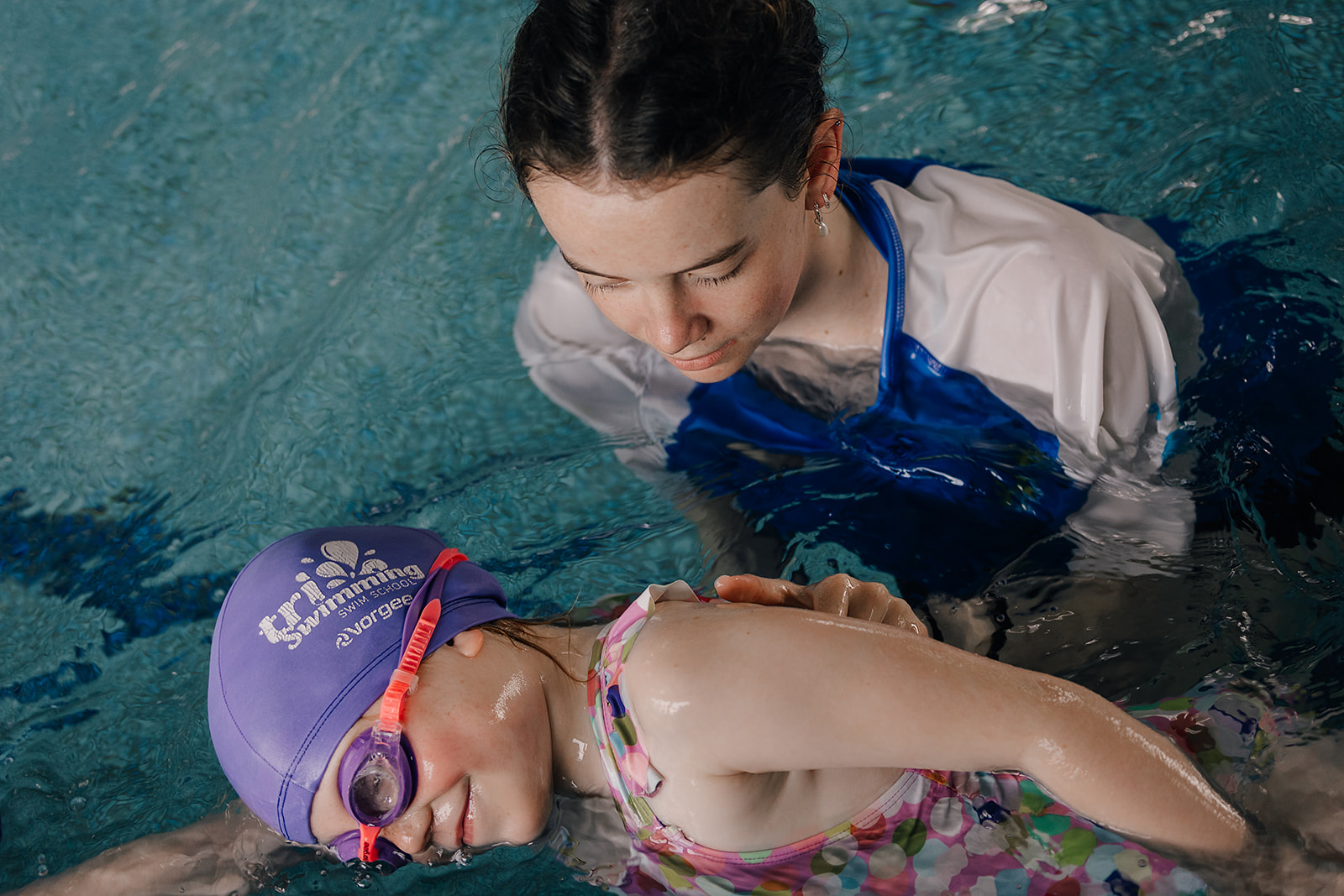 Smiling teacher with child in the pool